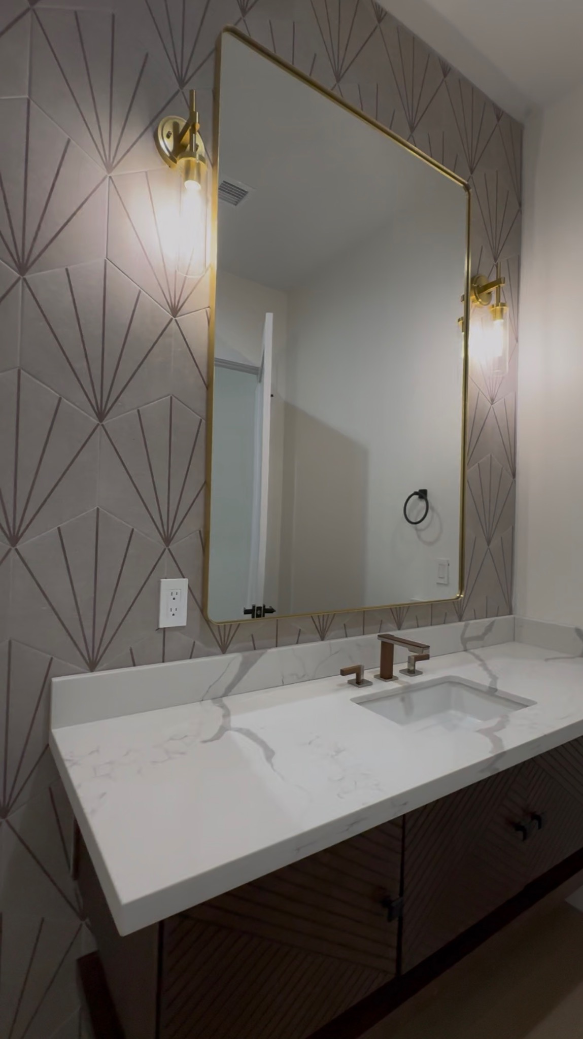 Bathroom vanity remodel with gold mirror and patterned tile wall